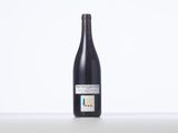 a bottle of red wine sitting on top of a white table