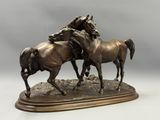 sculpture en bronze représentant deux chevaux, posée sur un socle en bois avec un fond gris