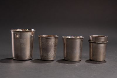 quatre verres à shot en argent posés les uns à côté des autres sur une table