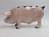 a ceramic pig that is standing on a white surface