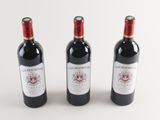 three bottles of red wine are lined up on a white surface