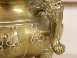 a large brass urn on a table with a picture in the background