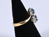 a close up of a gold ring with blue stones on a black ring stand