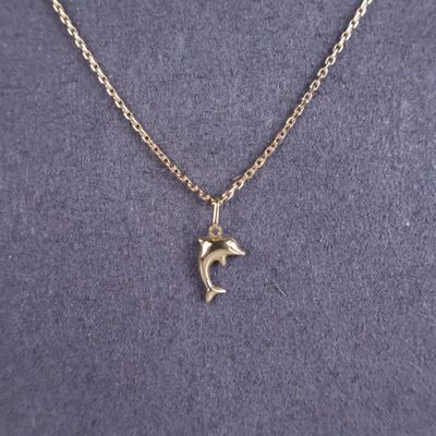 un collier avec un pendentif en forme de dauphin sur une chaîne en or