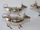 three silver cow figurines sitting on a white surface