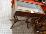 a wooden table with a glass top on a tile floor