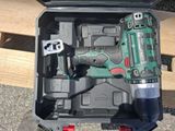 a green and black drill in a case with tools in it