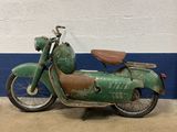 rusty green motorbike parked in front of a blue and white wall