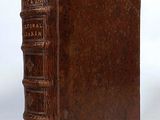 an old brown book sitting on top of a table next to a white wall
