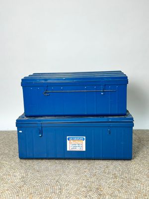 two blue storage boxes sitting on top of a carpeted floor