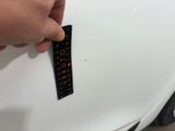 a hand that is holding a remote control in front of a white car