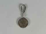 an image of a silver coin with a keychain on a white surface