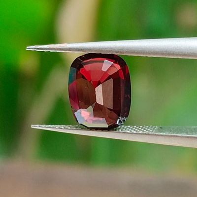 un gros plan d'un diamant rouge tenu par une pince