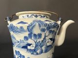 blue and white teapot with a handle on a black table