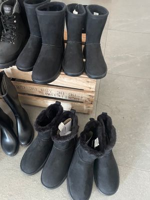 several pairs of black boots are lined up on a wooden crate