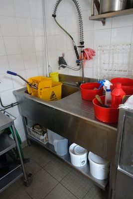 une cuisine avec un évier et de nombreux seaux posés sur le plan de travail