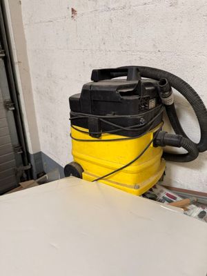 un aspirateur jaune et noir posé sur une table blanche