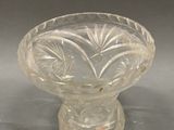 a clear glass bowl on a stand on a gray surface