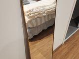 a mirror in the corner of a room with a bed in the background
