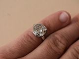 a woman ' s hand holding a ring with a diamond on it
