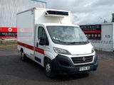 un camion blanc orné d'une bande rouge, garé devant un immeuble