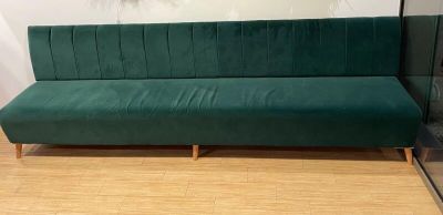 Le canapé vert est posé sur le parquet, devant la porte vitrée.