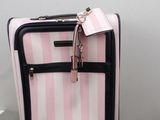 a pink suitcase with a tag on it sitting on the floor