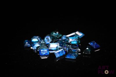 some blue glass pieces are scattered on a black surface