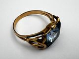 a close up of a gold ring with a blue topaz stone