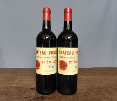 two bottles of red wine sitting on top of a wooden table