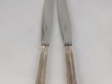 pair of silver plated cheese knives on a white surface