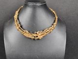 a gold necklace on a mannequin display with a black background