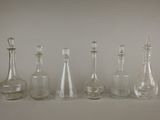 six carafes en verre sont alignées sur une surface blanche