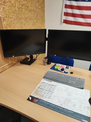 un bureau équipé de deux écrans et d'un clavier