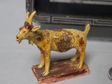 a figurine of a goat on a table with a spoon