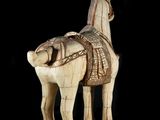 statue of a horse with a saddle on its back on a black background