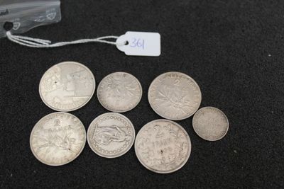 several silver coins sitting on top of a black surface next to a tag