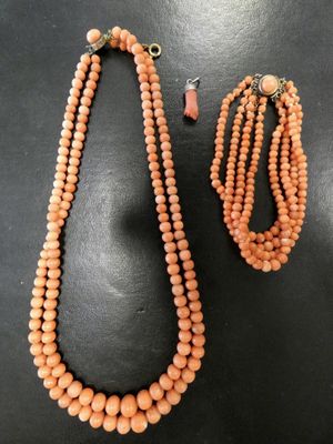 un collier et un bracelet composés de perles de corail sur un fond noir