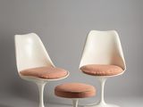 two white tulip chairs and a stool with a pink cushion