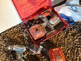 une mallette rouge contenant des outils et d’autres objets, posée par terre