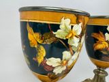two vases with flowers painted on them sitting on a table