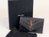 un portefeuille Saint Laurent noir avec une pochette noire et un sac noir