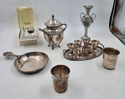 Plusieurs objets plaqués argent sont disposés sur une surface blanche