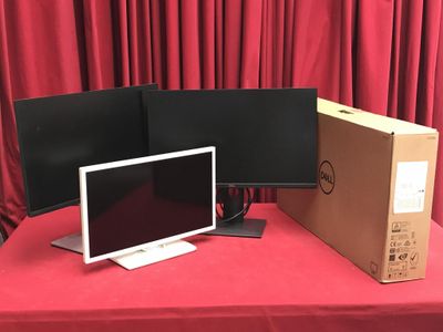 deux écrans et un ordinateur portable posés sur une table recouverte d'une nappe rouge