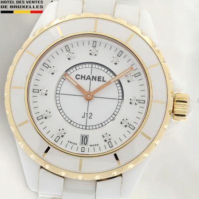 un gros plan d'une montre posée sur une surface blanche, rehaussée de touches dorées