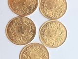 quatre pièces d'or sont disposées en ligne sur une surface blanche