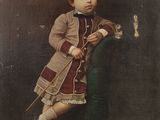 portrait of a young boy in a coat and dress holding a cane