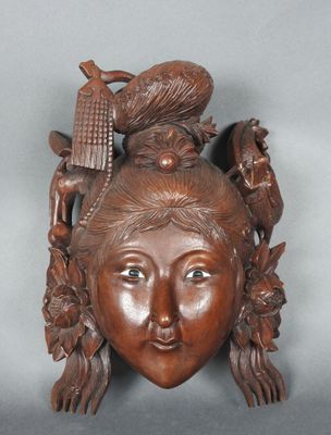 une image représentant une sculpture en bois représentant le visage d'une femme avec un oiseau sur la tête