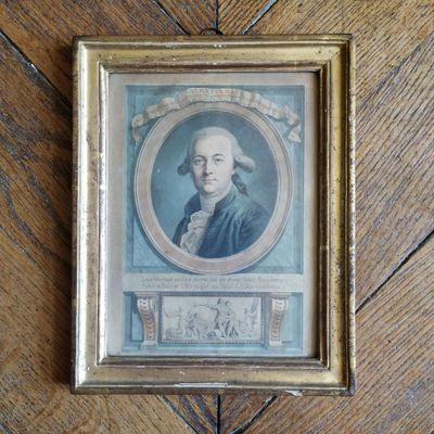 une vieille photo représentant un homme en manteau bleu, assis devant un parquet