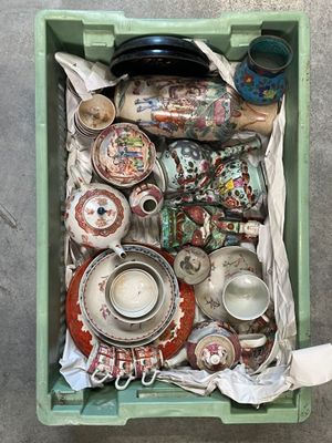 une boîte verte posée par terre et remplie d'objets divers